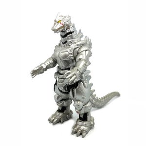 May include: A silver-colored, robotic Godzilla toy figure. The figure has a detailed design with articulated limbs, a spiked tail, and yellow eyes. The toy is standing on a white surface.