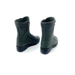 May include: A pair of dark green leather combat boots with laces. The boots are shown from the back, with the laces tied.