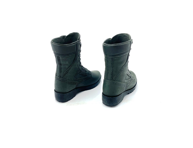 May include: A pair of dark green leather combat boots with laces. The boots are shown from the back, with the laces tied.