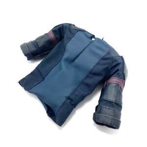 Puede incluir: Una chaqueta negra y azul con hombros y brazos acolchados. La chaqueta tiene una cremallera y un cuello alto.