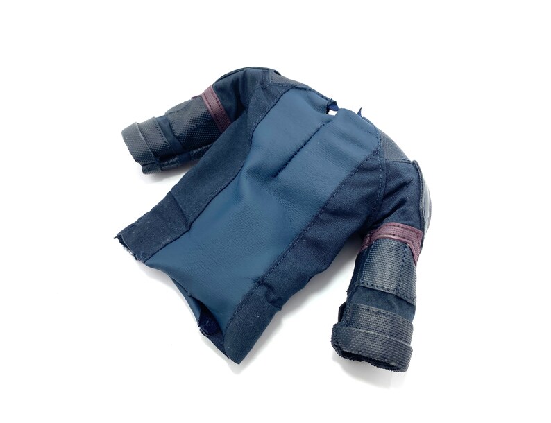 Puede incluir: Una chaqueta negra y azul con hombros y brazos acolchados. La chaqueta tiene una cremallera y un cuello alto.