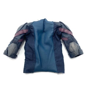 Puede incluir: Una camisa de tela azul oscuro y negra con detalles marrones. La camisa tiene una tela texturizada y un dise&ntilde;o de manga larga.