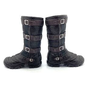 May include: A pair of brown leather boots with multiple buckles. The boots have a textured surface and a black sole.