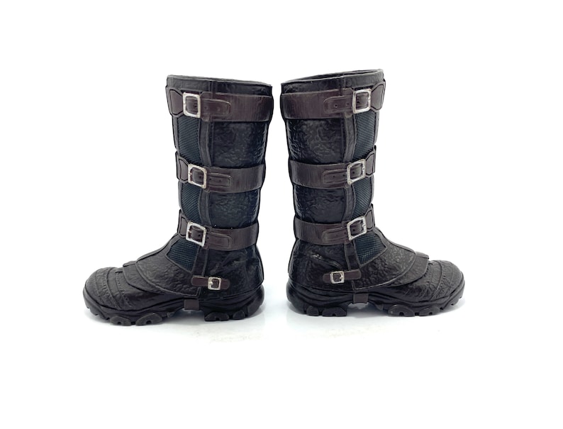 May include: A pair of brown leather boots with multiple buckles. The boots have a textured surface and a black sole.