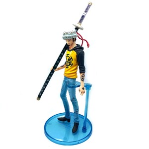 Pu&ograve; includere: Statuetta di un personaggio della serie anime One Piece. La figura indossa una felpa con cappuccio gialla con finiture nere, jeans blu e scarpe nere. La figura tiene in mano un bastone nero con stelle bianche e una spada. La figura &egrave; su un supporto blu.