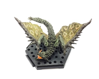 May include: A detailed figurine of a dragon with outstretched wings, featuring a green and gold color scheme. The dragon is mounted on a black hexagonal base. The wings have a textured pattern, and the dragon's mouth is open, revealing an orange interior.