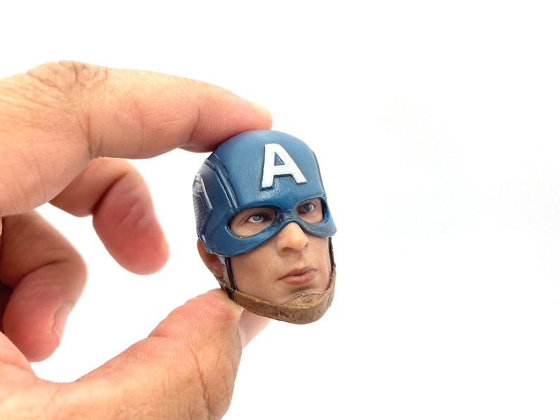 Puede incluir: Una escultura de cabeza de pl&aacute;stico azul y marr&oacute;n de Capit&aacute;n Am&eacute;rica, con su ic&oacute;nico casco con una "A" blanca en la parte delantera. El casco tiene una m&aacute;scara azul con una franja blanca sobre los ojos.