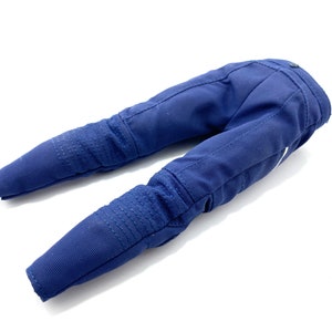 May include: A pair of blue denim trousers with knee pads. The trousers are folded in half and laid flat on a white surface.
