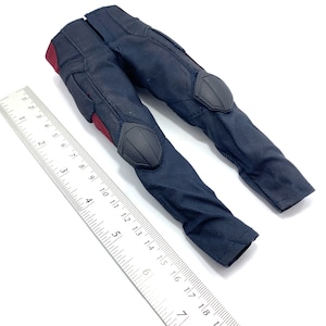 May include: Black trousers with red and grey accents. The trousers have knee pads and are made of a textured fabric.