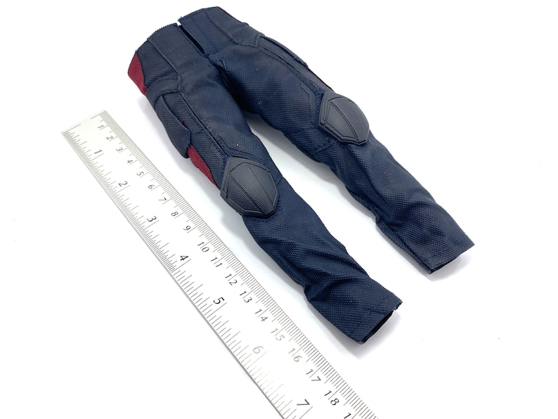 May include: Black trousers with red and grey accents. The trousers have knee pads and are made of a textured fabric.