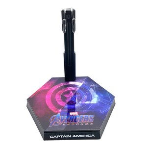 K&ouml;nnte beinhalten: Ein schwarzer Plastik-Actionfigurenst&auml;nder mit sechseckiger Basis. Die Basis zeigt eine Grafik von Captain Americas Schild mit den Worten "Marvel Avengers Endgame" und "Captain America" darauf.