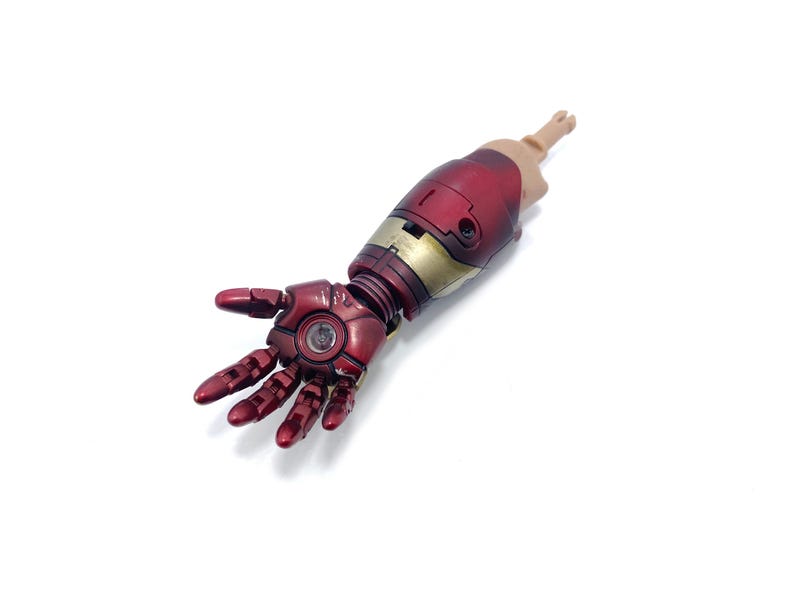 K&ouml;nnte beinhalten: Detaillierte Nachbildung eines Iron Man-Arms mit metallisch roter und goldener Farbgebung. Der Arm umfasst eine Hand mit beweglichen Fingern und einen Unterarm mit komplizierten mechanischen Details. Das Modell ist vor wei&szlig;em Hintergrund.