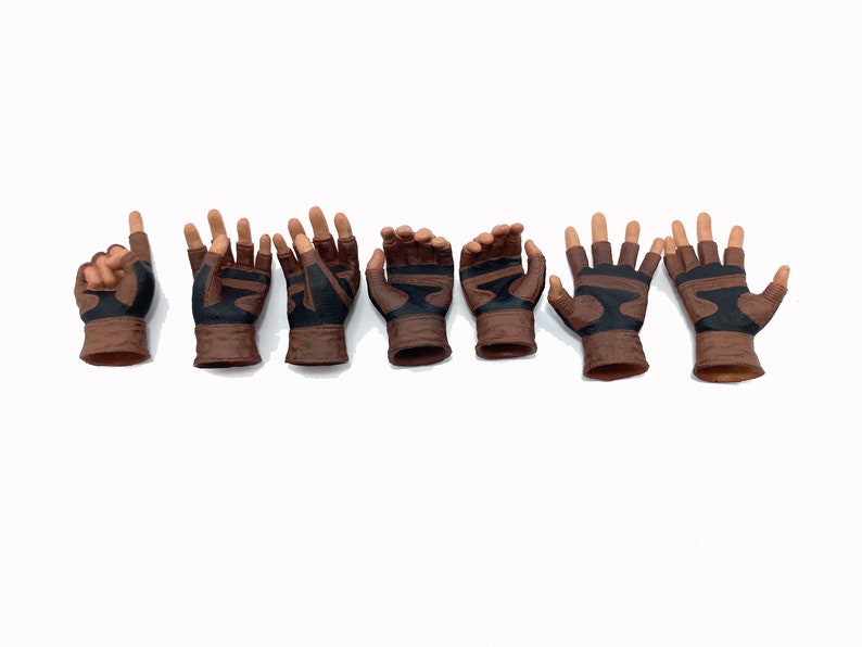 May include: Eight brown leather gloves with black accents. The gloves have different hand poses, including pointing, open palm, and fist.