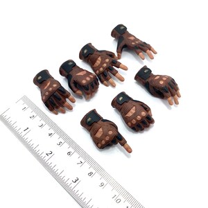 May include: Set of seven brown and black fingerless gloves with knuckle protection. The gloves have a textured leather look and are designed for action figures.