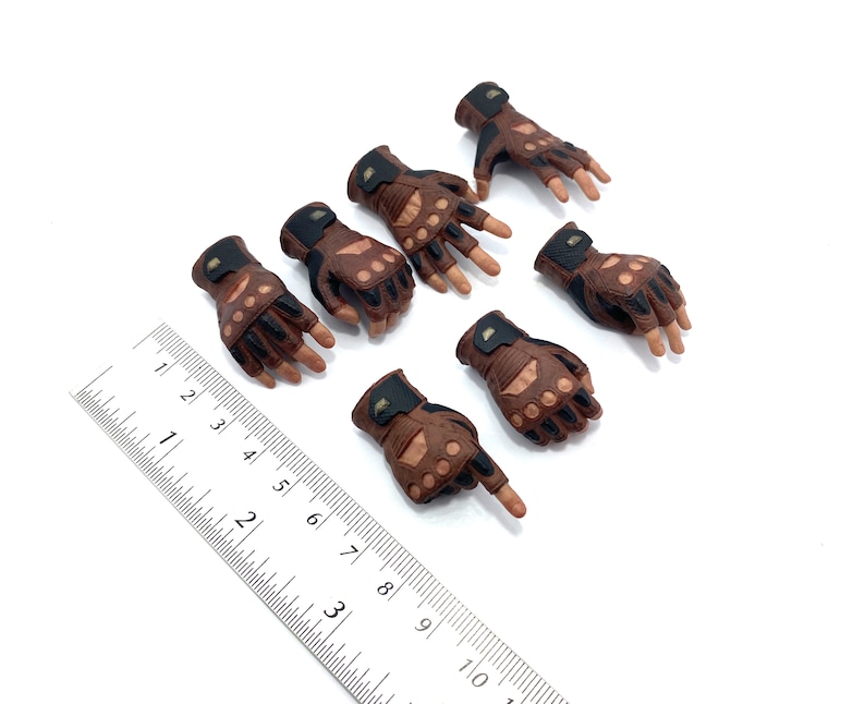 May include: Set of seven brown and black fingerless gloves with knuckle protection. The gloves have a textured leather look and are designed for action figures.