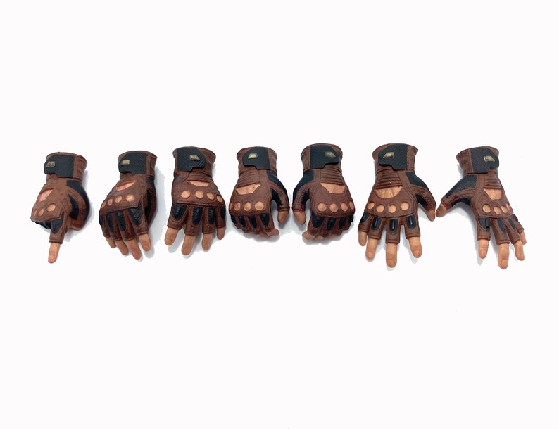 May include: Seven brown leather gloves with black accents and finger holes. The gloves are arranged in a row on a white background.