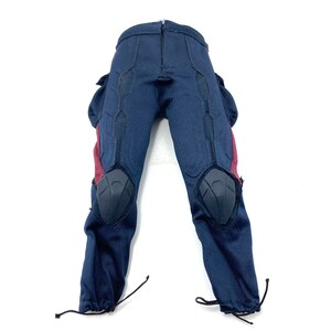 Puede incluir: Pantal&oacute;n azul con detalles rojos y negros. El pantal&oacute;n tiene rodilleras y bolsillos cargo.