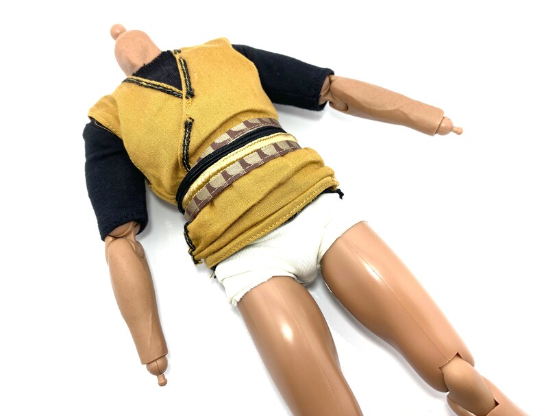 May include: A brown and black action figure wearing a yellow shirt, a brown and black belt, and white underwear.