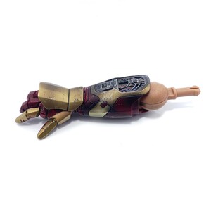 K&ouml;nnte beinhalten: Ein detaillierter, beweglicher Actionfigurenarm in Metallic-Gold und Burgunderrot. Der Unterarm zeigt mechanische Details, die Hand ist teilweise geschlossen. Ein Sammlerst&uuml;ck, wahrscheinlich aus einer bekannten Franchise.