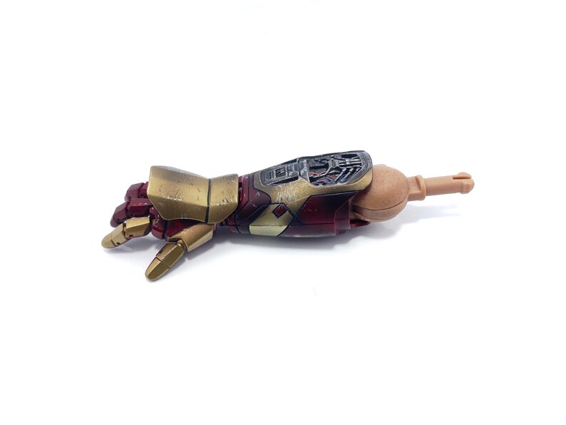 K&ouml;nnte beinhalten: Ein detaillierter, beweglicher Actionfigurenarm in Metallic-Gold und Burgunderrot. Der Unterarm zeigt mechanische Details, die Hand ist teilweise geschlossen. Ein Sammlerst&uuml;ck, wahrscheinlich aus einer bekannten Franchise.