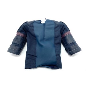 Puede incluir: Una camiseta de figura de acci&oacute;n negra y azul con una cremallera en la espalda y detalles marrones en las mangas.