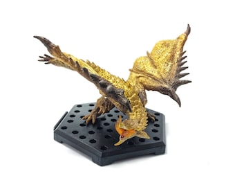 May include: A gold and brown dragon figurine with a black base. The dragon has a spiky back and wings, and its mouth is open in a roar.