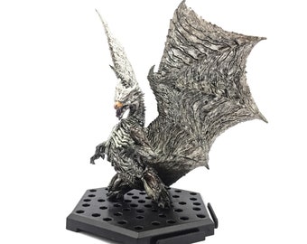 May include: A detailed figurine of a dragon with outstretched wings, featuring a textured, gray and white color scheme. The dragon is posed on a black hexagonal base. The dragon's wings are large and detailed, with a textured appearance.