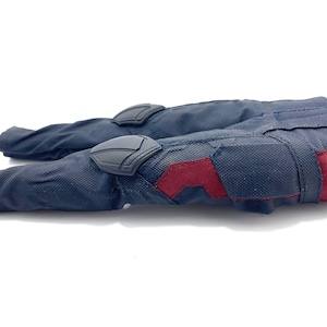 May include: A pair of dark blue trousers with red and black accents. The trousers have reinforced knee pads and a zipped pocket on the right leg.
