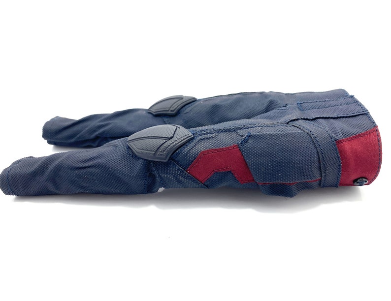 May include: A pair of dark blue trousers with red and black accents. The trousers have reinforced knee pads and a zipped pocket on the right leg.