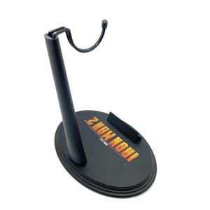 May include: Black plastic action figure stand with a hook and a circular base. The base has the words "IRON MAN 2" printed on it in yellow and orange.