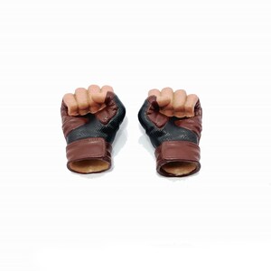 Op de afbeelding: Een paar bruine en zwarte leren handschoenen met een textuurontwerp. De handschoenen zijn gemaakt voor action figures en hebben een realistische uitstraling.