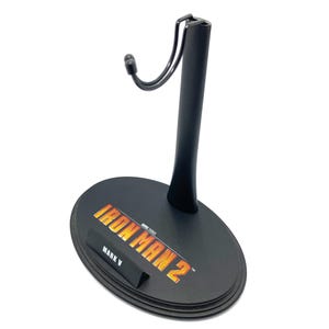 May include: Black plastic action figure stand with a metal hook. The base of the stand has the words "Iron Man 2" and "Mark V" printed on it.