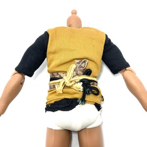 May include: A yellow sleeveless shirt with a black undershirt and a brown and gold belt. The shirt is torn at the bottom.