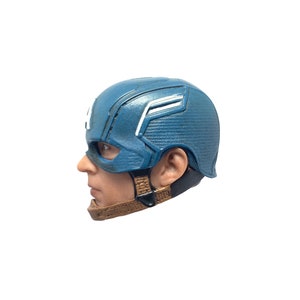 Puede incluir: Un casco de pl&aacute;stico azul y blanco de Capit&aacute;n Am&eacute;rica con una correa marr&oacute;n. El casco est&aacute; dise&ntilde;ado para parecerse al que usa el superh&eacute;roe en las pel&iacute;culas de Marvel.