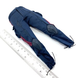 Puede incluir: Un par de pantalones azul oscuro con detalles rojos y rodilleras negras. Los pantalones tienen un cord&oacute;n en la parte inferior de cada pierna.