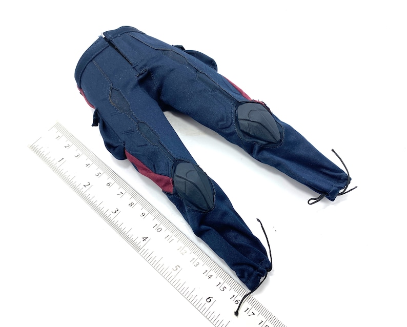 Puede incluir: Un par de pantalones azul oscuro con detalles rojos y rodilleras negras. Los pantalones tienen un cord&oacute;n en la parte inferior de cada pierna.