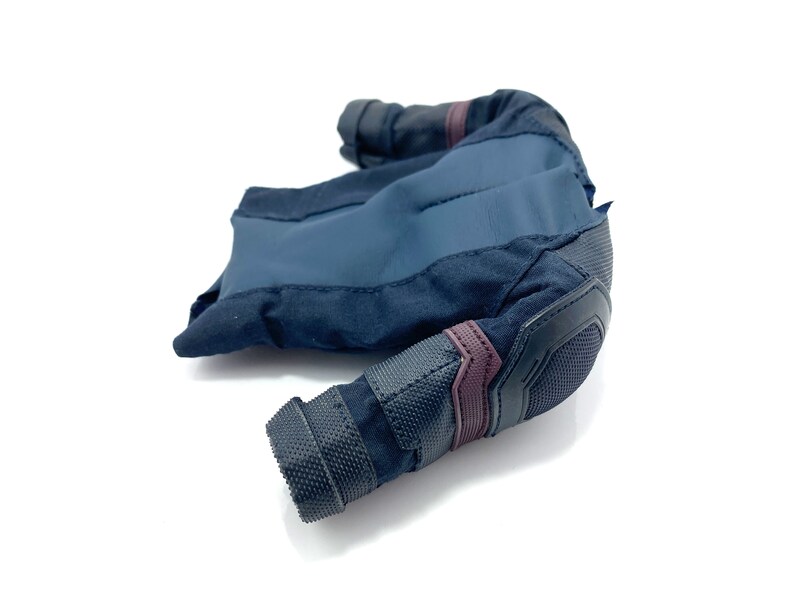 Puede incluir: Una chaqueta de tela azul oscuro y negro con cierre de cremallera y un panel de malla en el codo. La chaqueta tiene una tela texturizada y un acento burdeos en el codo.