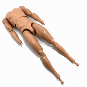 May include: A tan-coloured articulated action figure body, featuring a muscular torso, arms, and legs. The figure has multiple points of articulation for posing and display. The figure is lying on a white surface.