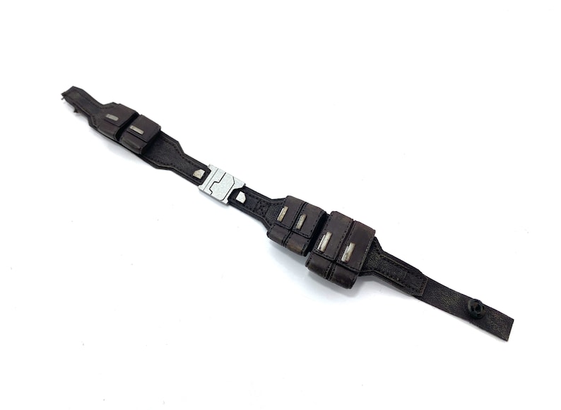 May include: A brown leather belt with a silver buckle and multiple pouches. The belt has a black button on the end.