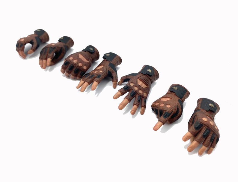 May include: Eight brown leather gloves with black accents and finger holes. The gloves have a textured surface and are designed for action figures.