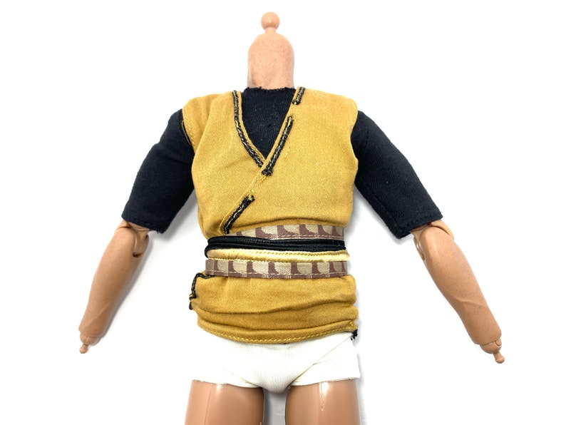 May include: A yellow sleeveless shirt with black trim and a brown and gold belt. The shirt is worn over a black short-sleeved shirt.