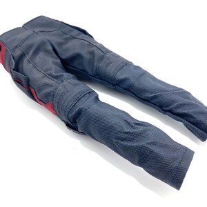 May include: Black trousers with red accents. The trousers have a textured fabric and are designed for motorcycle riding.