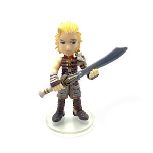 May include: A figurine of a blonde-haired warrior holding a large curved sword. The figure is wearing brown and tan armor with a detailed design. The figurine is standing on a clear, circular base.