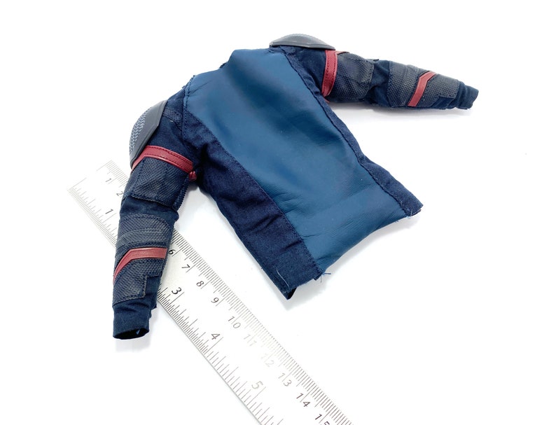 Op de afbeelding: Een blauw en zwart actieve figuurjack met rode accenten. Het jack heeft een ritssluiting en een opstaande kraag.