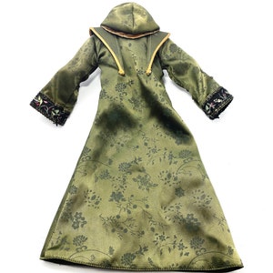 Op de afbeelding: Een lange groene robe met een bloemenpatroon en een capuchon. De robe heeft zwarte en gouden bies en een gouden koord.