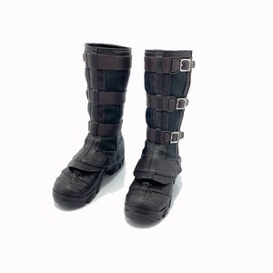 May include: A pair of brown leather boots with black mesh panels and multiple buckles. The boots have a rugged, textured sole.