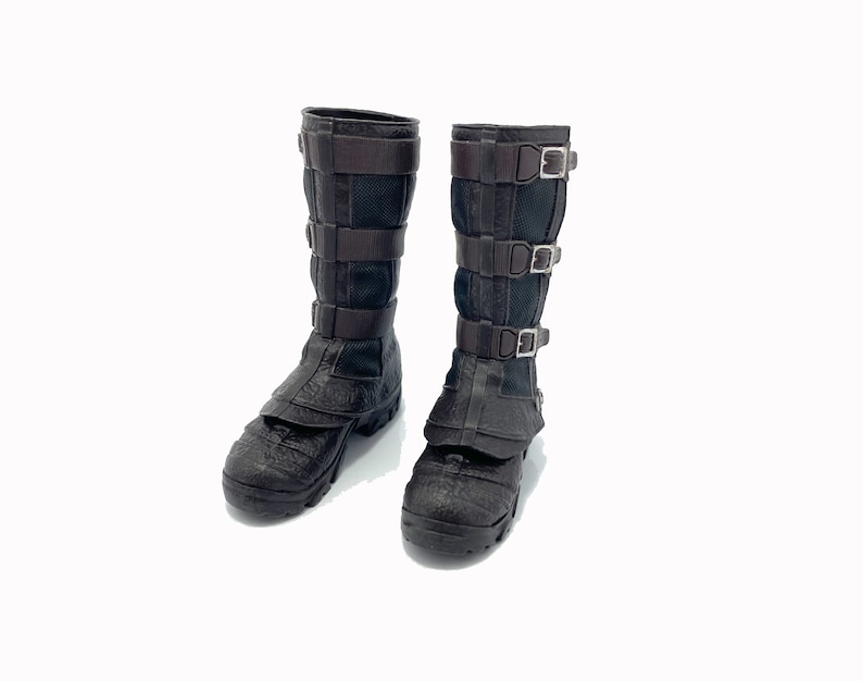 May include: A pair of brown leather boots with black mesh panels and multiple buckles. The boots have a rugged, textured sole.