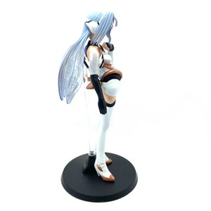 May include: A detailed figurine of a character with long, light blue hair and a white and brown outfit. The figure stands on a black circular base with a clear support rod. The figure has a dynamic pose and intricate design.