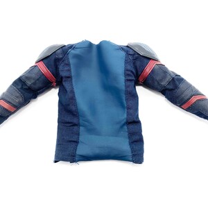 Op de afbeelding: Een blauw en zwart langarm shirt met rode accenten en gevoerde schouders. Het shirt is gemaakt van een zachte, textuurrijke stof.