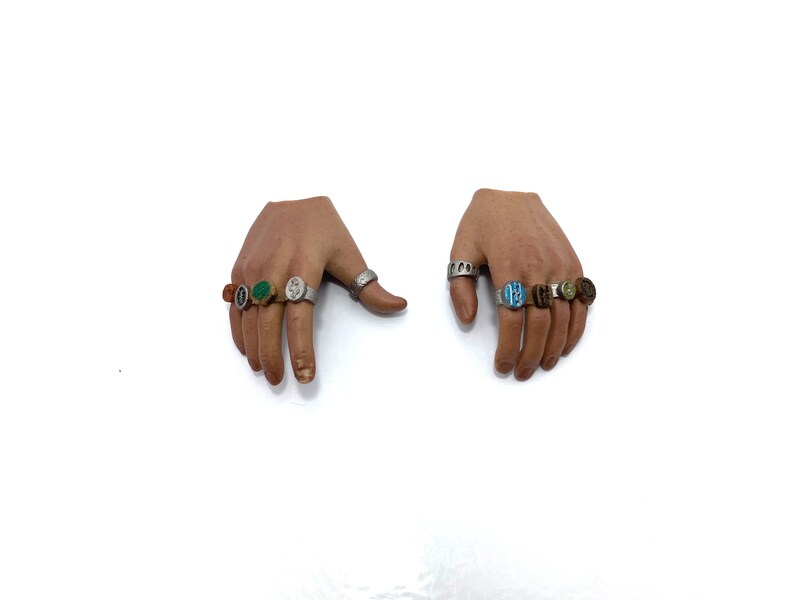 Puede incluir: Dos manos con m&uacute;ltiples anillos en cada dedo. Los anillos son de plata con piedras de diferentes colores, incluyendo verde, azul, naranja y marr&oacute;n.